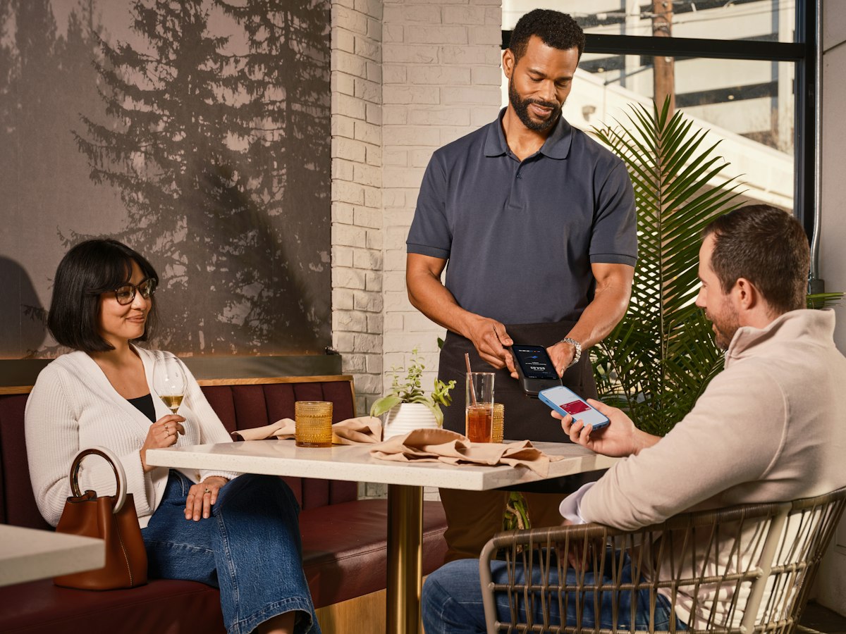Gast bezahlt am Restauranttisch mit dem Smartphone